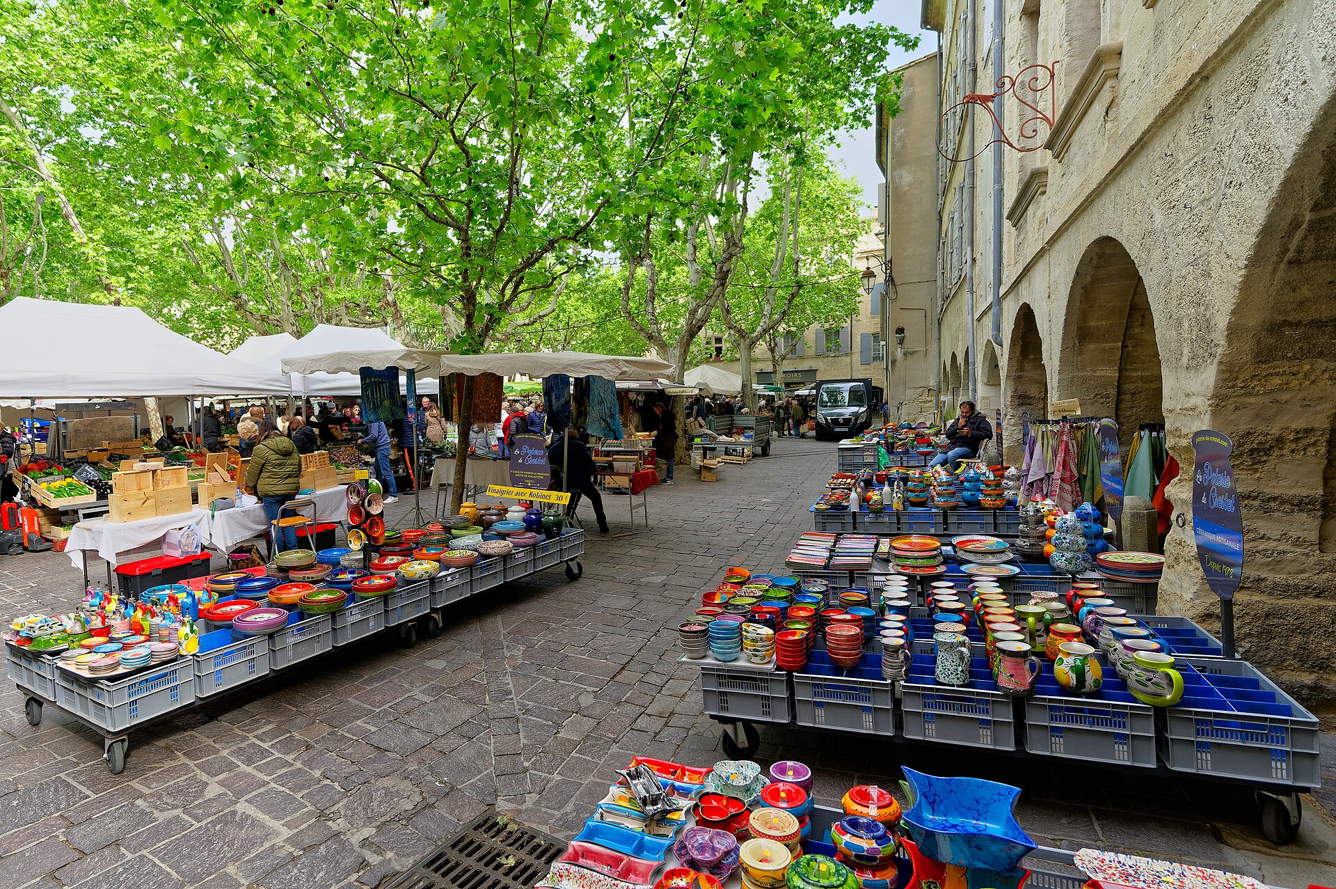 Le marché d'Uzès sous les platanes de la place aux Herbes, étals de poteries et de primeurs