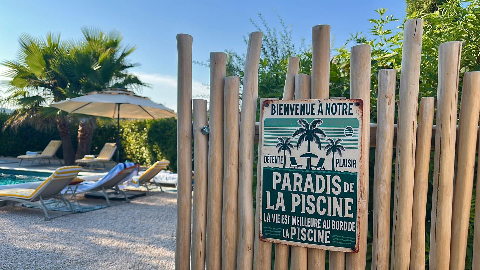 Le panneau « Paradis de la piscine » sur la ganivelle, au bord du bassin