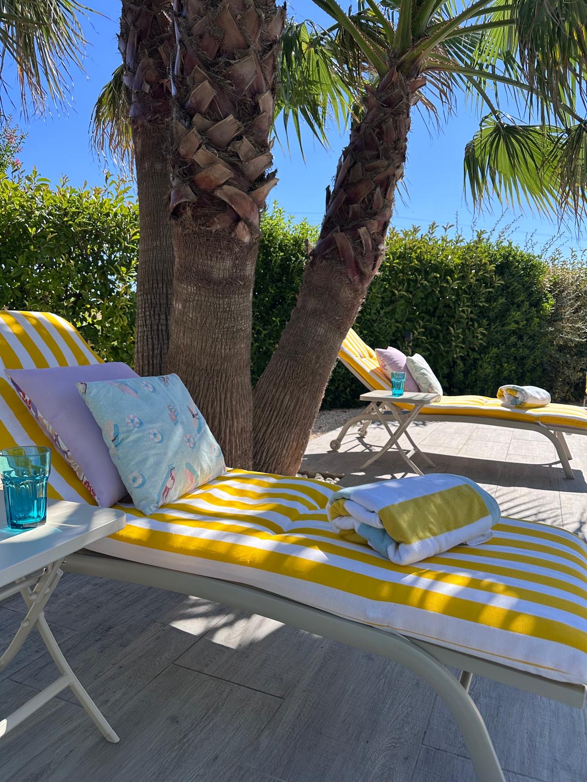 Serviettes de piscine pliées sur un transat, au bord du bassin