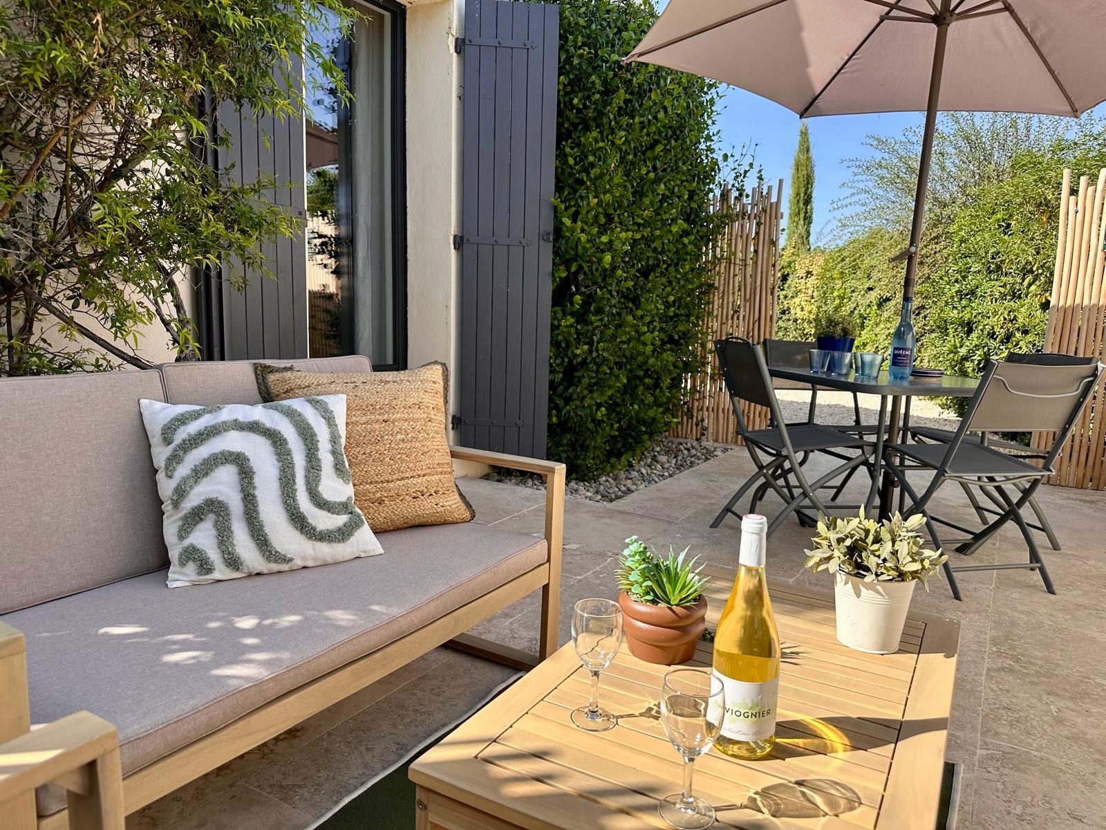 Salon de jardin en bois sur la terrasse privative, à l'ombre du parasol