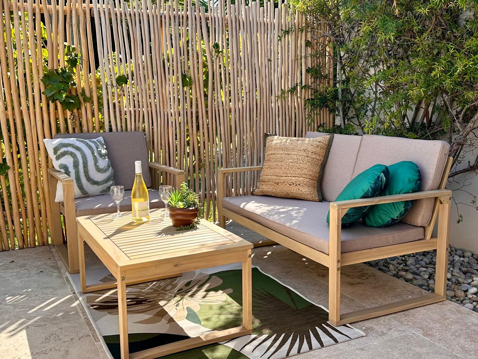 Le canapé et les fauteuils de la terrasse, derrière la ganivelle