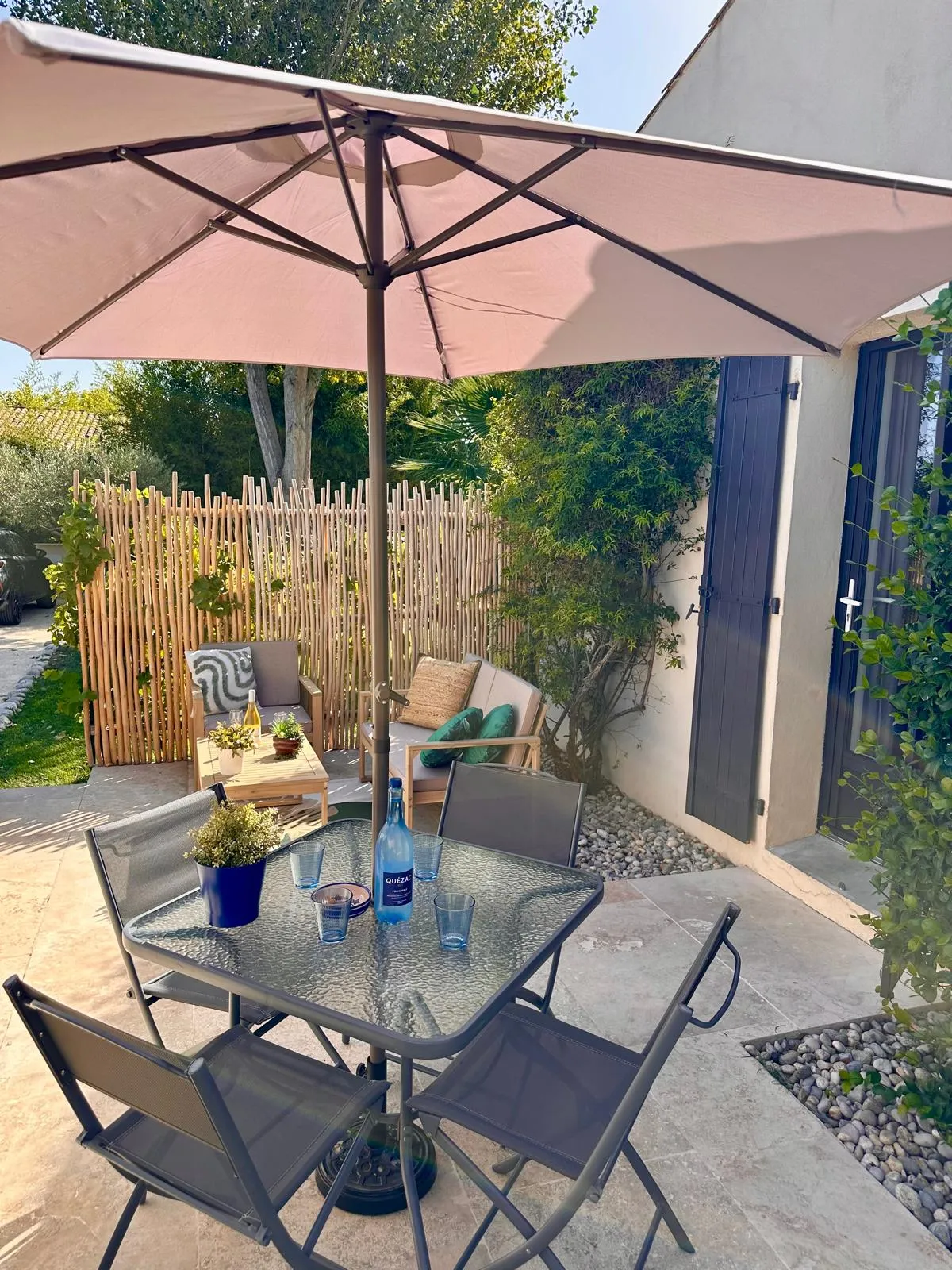 Die private Terrasse: Tisch unter dem Sonnenschirm und Gartensofa hinter dem Staketenzaun